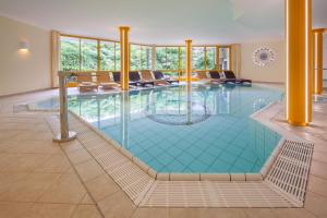 a pool in a hotel with chairs and a large room at Hotel Birgsau in Oberstdorf