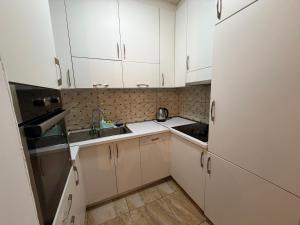 a small kitchen with white cabinets and a sink at Cozzy Apartment in Prishtinë