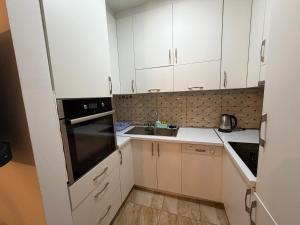 a small kitchen with white cabinets and a sink at Cozzy Apartment in Prishtinë