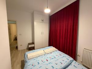 a bedroom with a bed and a red curtain at Cozzy Apartment in Prishtinë