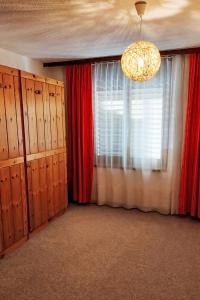 a room with a window with red curtains and a chandelier at Apartment Orion by Interhome in Leukerbad