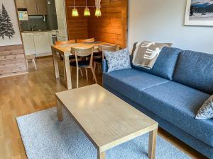 a living room with a blue couch and a table at Holiday Home Ylläs chalets a307 by Interhome in Ylläs