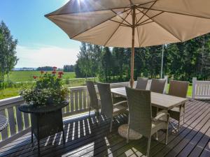 a wooden table with chairs and an umbrella on a deck at Holiday Home Kannelpirtti 2 by Interhome in Puromäki
