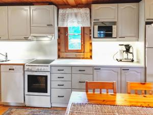 a kitchen with white appliances and a wooden table at Holiday Home Eskola by Interhome in Lahdenperä