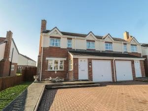 a large brick house with two white garage doors at Sandy Cove in Chathill