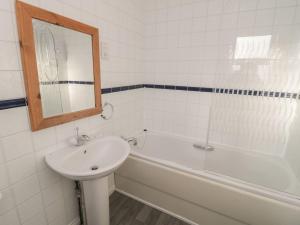 a bathroom with a sink and a tub and a mirror at Sandy Cove in Chathill +21 photos