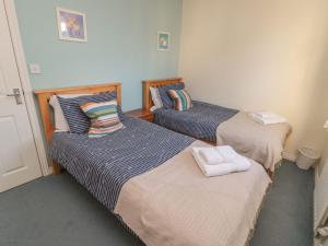 two beds in a room with towels on them at Sandy Cove in Chathill