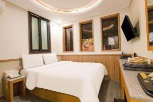 a large white bed in a room with windows at Yeongdeungpo Komodo Hotel in Seoul