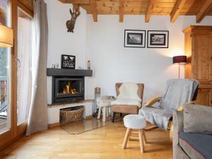 a living room with a fireplace and two chairs at Chalet Ropiar by Interhome in Ovronnaz
