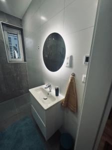 a white bathroom with a sink and a mirror at Štúdio Sihoť - parkovanie a nabíjanie EV in Trenčín +6 photos