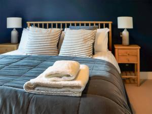 a bed with a blue comforter with towels on it at Headlands Hideaway in Coverack