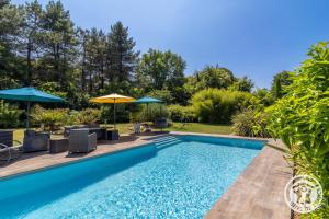 a pool with chairs and umbrellas in a yard at Ecrin de Verdure Spa, Piscine et Nature in Angrie