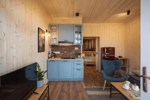 a kitchen and living room with blue cabinets at Apartamenty Leśna Przystań nad jeziorem in Węgorzewo