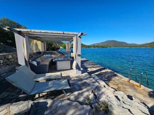 a pergola and couch on a dock on a lake at Apartment Waterfront Oasis-3 by Interhome in Mali Ston
