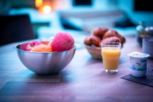a bowl of fruit on a table with a glass of orange juice at LSWDB Suite Soma in Bassenge