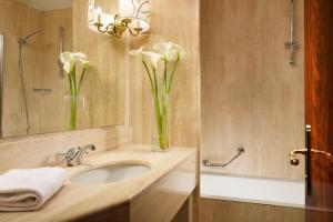 a bathroom with a sink with flowers in a vase at UNA Hotels Scandinavia Milano in Milan +31 photos