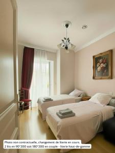 a hotel room with two beds and a window at La Rose du Château in Lourdes