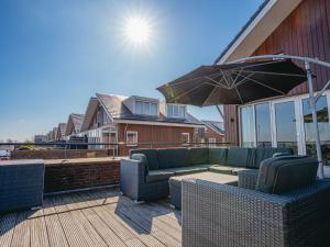 a patio with a couch and an umbrella on a deck at Apartment Oostergeest 2 by Interhome in Uitgeest