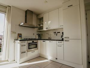 a white kitchen with white cabinets and a window at Apartment Oostergeest 2 by Interhome in Uitgeest +28 photos