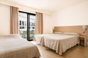 a hotel room with two beds and a balcony at Apartamentos San Francisco in San Antonio
