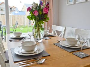 a table with plates and a vase of flowers on it at Llifon in Llanwnda