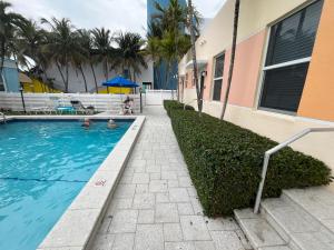 a swimming pool next to a building with palm trees at Beachside One Bedroom Condo with Pool Access in Hollywood