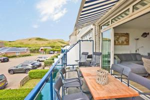 a balcony with a wooden table and chairs at Seinpost Appartment in Callantsoog