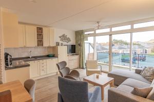 a kitchen and living room with a couch and a table at Seinpost Appartment in Callantsoog +20 photos