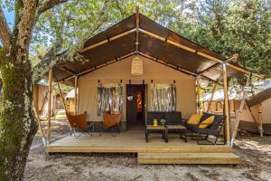 a tent with chairs and a table in front of a tree at Easyatent Camping Cikat in Mali Lošinj