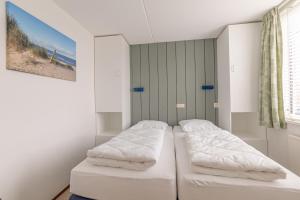 two beds in a room with white walls at Seinpost Appartment in Callantsoog