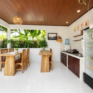 a kitchen with a wooden ceiling and a table and chairs at Putra Bali Villa by Antara in Klungkung
