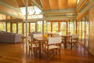 a dining room with a table and chairs and windows at Bombah Point Eco Cottages in Bulahdelah