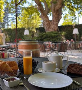 a table with a plate of food and a glass of orange juice at Logis Hotel le Mas De Cure Bourse in L'Isle-sur-la-Sorgue