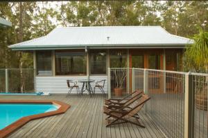 a house with a deck with a table and chairs at Bombah Point Eco Cottages in Bulahdelah