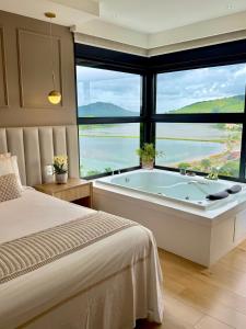 a bedroom with a large tub in front of a window at Vista do Lago Hotel in Capitólio