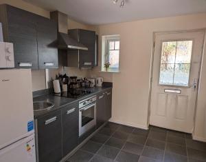 a kitchen with gray cabinets and a sink and a door at Sherlock's Moray House -Idea long stay for contractors & family Two bedroom mid terrace 3 beds 2 sofa beds Sleep 5 Working facility Free WiFi TV & private parking Enclose rear garden dog friendly Sainsbury's & takeaway pubs in walking distance in Church Gresley