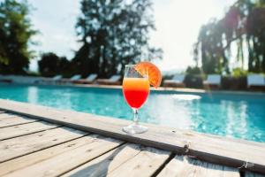 a glass of orange juice sitting on a table next to a pool at ZEcamping 2 étoiles accès direct à la plage chiens acceptés piscine in Ghisonaccia
