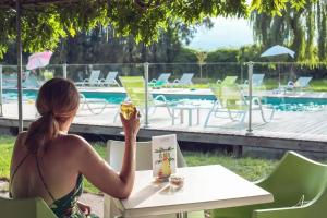 a woman sitting at a table near a pool at ZEcamping 2 étoiles accès direct à la plage chiens acceptés piscine in Ghisonaccia