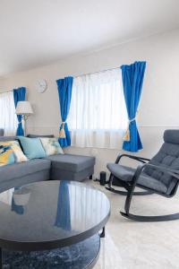 a living room with blue curtains and a couch and a table at Sunstone Residence 2F - Free Rental Car & Airport Pickup - 10 Min to American Village in Ginowan