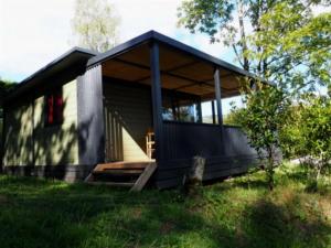 a small black house with a porch at ZEcamping 4 étoiles animaux acceptés tennis piscine couverte in Vic-sur-Cère