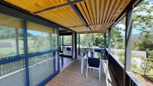 a wooden deck with chairs and a wooden ceiling at ZEcamping 4 étoiles animaux acceptés tennis piscine couverte in Vic-sur-Cère