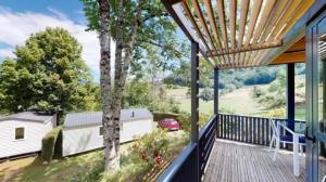 a deck with a view of a house with a car on it at ZEcamping 4 étoiles animaux acceptés tennis piscine couverte in Vic-sur-Cère