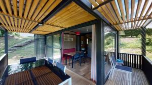 a screened porch with a wooden roof and a table at ZEcamping 4 étoiles animaux acceptés tennis piscine couverte in Vic-sur-Cère +71 photos