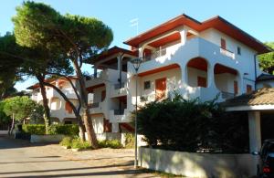 a white building with a tree in front of it at Residence Sporting in Rosolina Mare