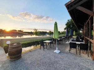 a patio with tables and chairs and a green umbrella at ZEcamping 3 étoiles animaux acceptés espace aquatique in Moncontour-de-Poitou