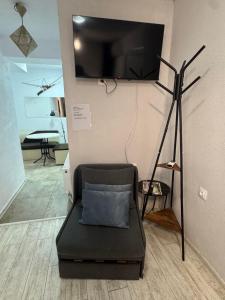 a living room with a tv and a chair with a pillow at Berta Gardens 2 in Sandanski