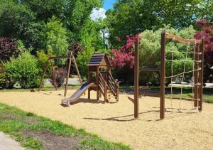 a playground with two swings and a slide at Camping La Clairière - Aquatique Vacances in Saint-Paul-en-Born