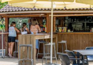 a couple of people standing at a bar at Camping La Clairière - Aquatique Vacances in Saint-Paul-en-Born