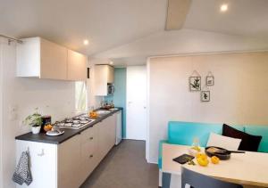 a kitchen with white cabinets and a table in a room at Camping La Clairière - Aquatique Vacances in Saint-Paul-en-Born +5 photos
