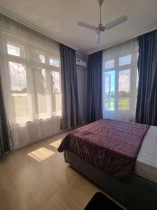 a bedroom with a bed and two large windows at Legacy Homes in Dar es Salaam